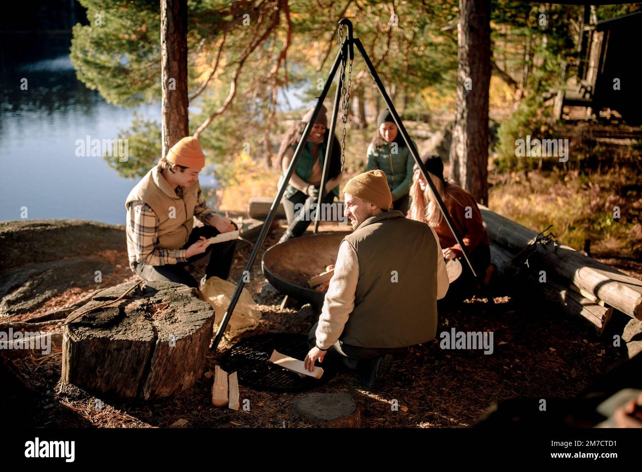 Multirassische Freunde verbringen ihre Freizeit, während sie beim Camping in der Nähe der Feuerstelle sitzen Stockfoto
