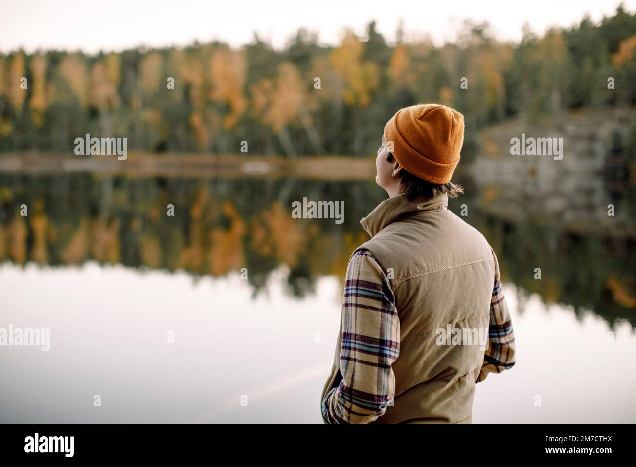 Rückansicht eines jungen Mannes mit Hand in der Tasche, der Zeit am See verbringt Stockfoto