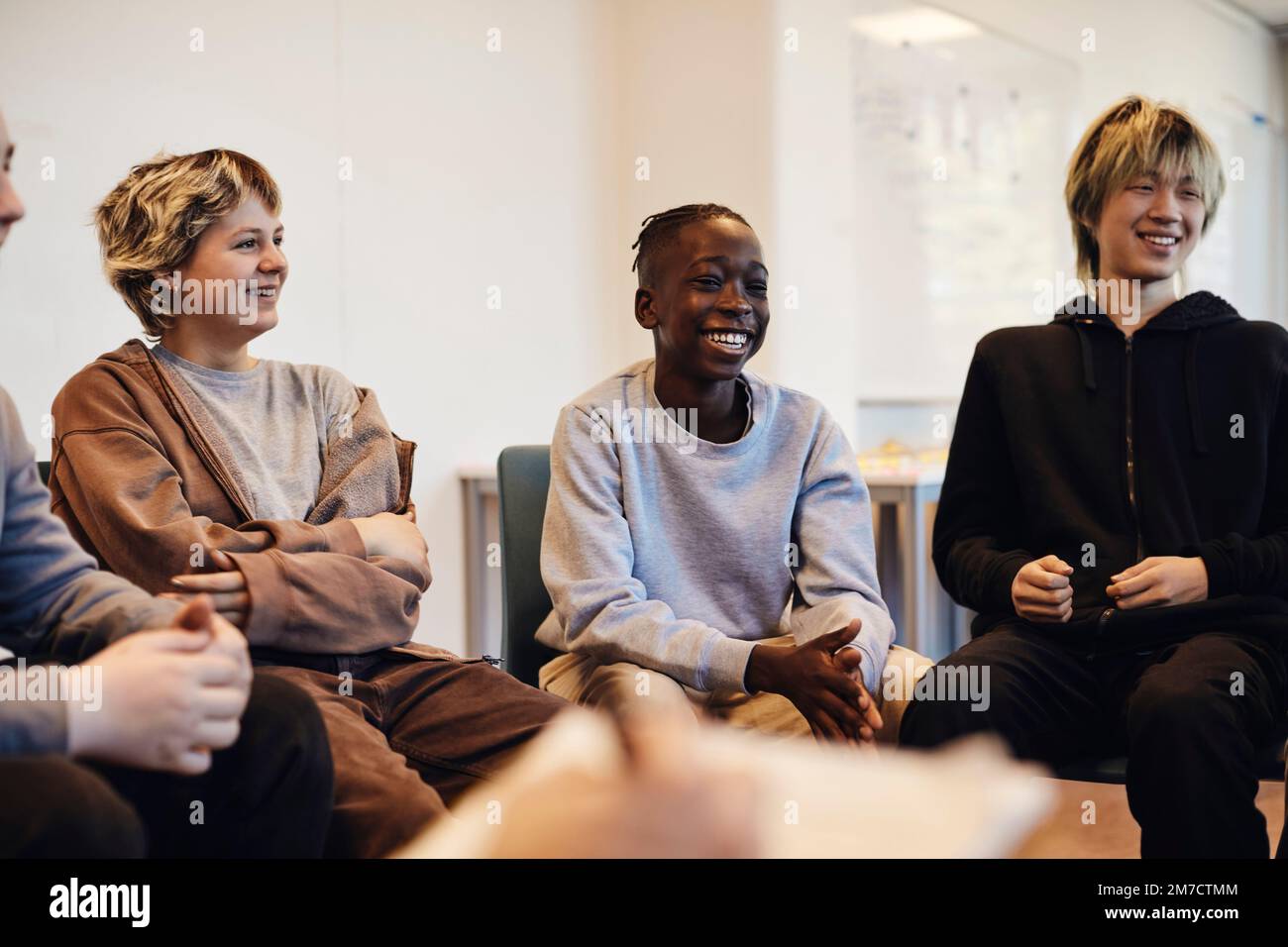 Glückliche Teenager Jungs und Mädchen sitzen zusammen in der Gruppentherapie Stockfoto