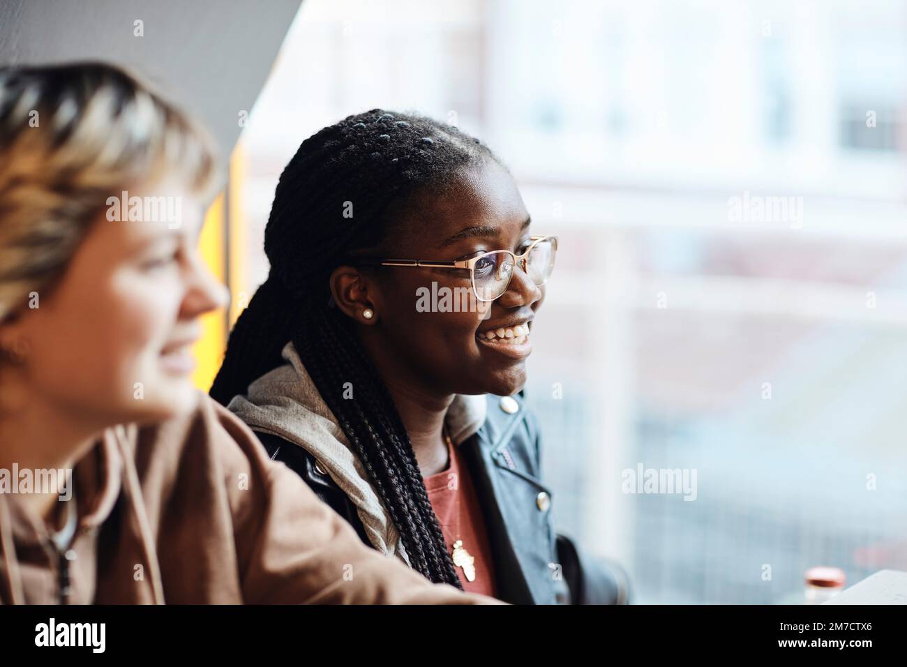 Glückliches Teenager-Mädchen mit geflochtenen Haaren, das eine Brille von einer Freundin trägt Stockfoto