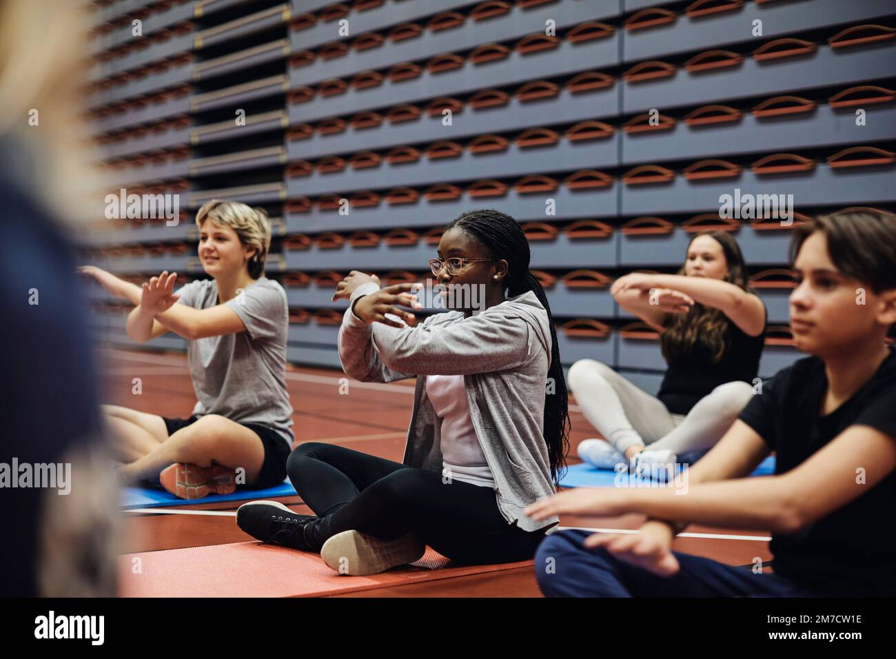 Teenager Mädchen und Jungen Gesten beim Yoga-Training auf dem Sportplatz Stockfoto