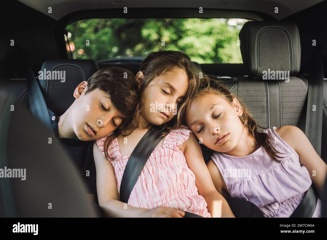 Müde Geschwister schlafen auf dem Rücksitz, während sie im Auto unterwegs  sind Stockfotografie - Alamy