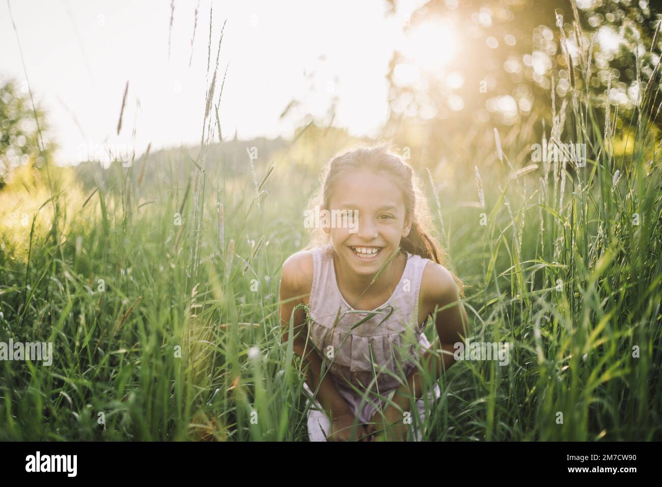 Porträt eines glücklichen Mädchens, das an sonnigen Tagen im Gras spielt Stockfoto