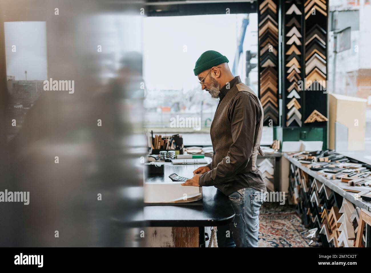 Männlicher Unternehmer, der auf einer Werkbank in einer Rahmenwerkstatt steht Stockfoto