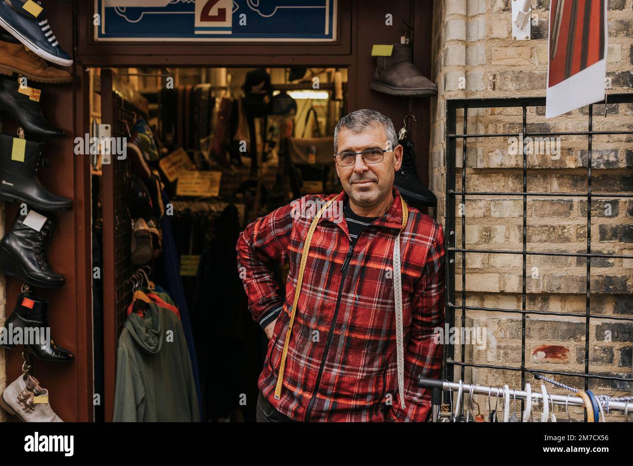 Porträt eines erwachsenen Besitzers, der mit der Hand an der Hüfte steht, ausserhalb des Bekleidungsgeschäfts Stockfoto