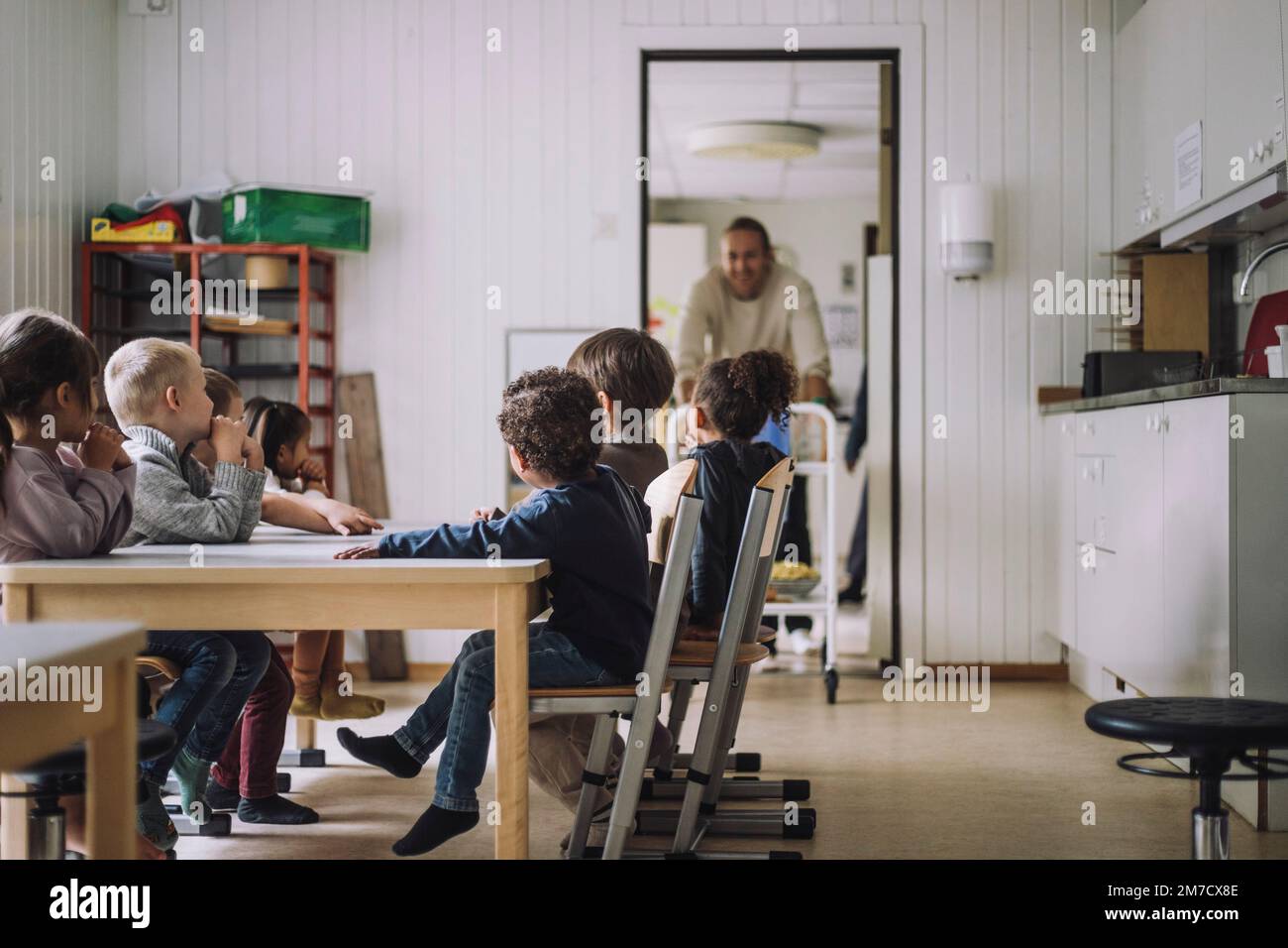 Multirassische männliche und weibliche Studenten sitzen während des Frühstücks im Kindergarten am Esstisch Stockfoto