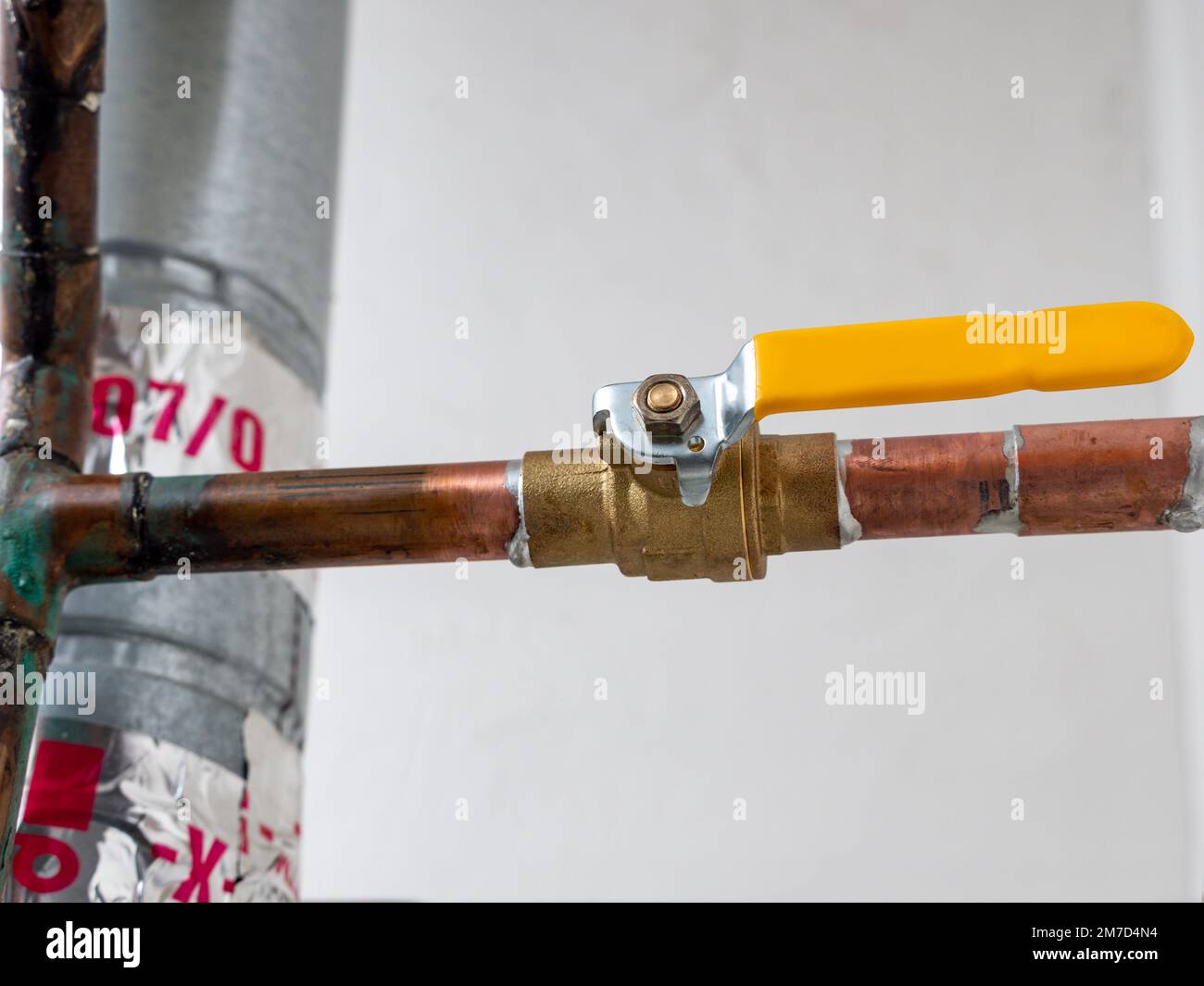 Wasserabsperrventil. Kupferrohrleitung mit Messing-Wasserversorgungsventil und gelbem Hahngriff. Stockfoto