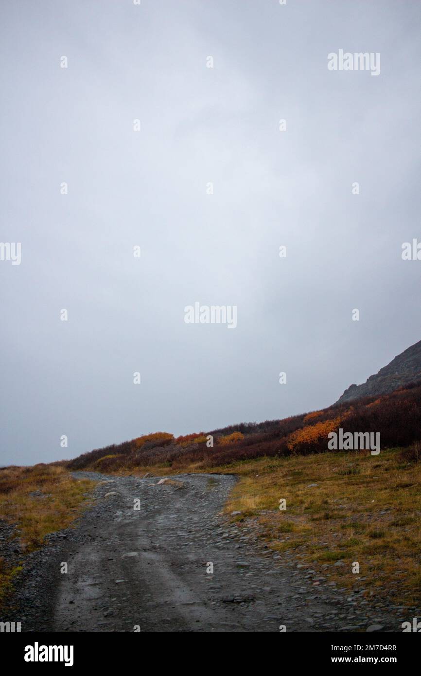 Ein vertikales Bild einer Schotterstraße im Berggebiet im Herbst in Murmansk, Russland Stockfoto