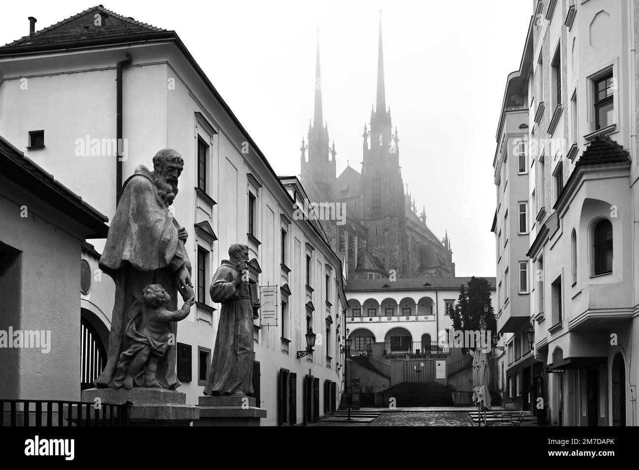 Alte Straßen in Brünn mit Statuen und der Kathedrale von St. Peter und Paul im Winter in Schwarz und Weiß Stockfoto