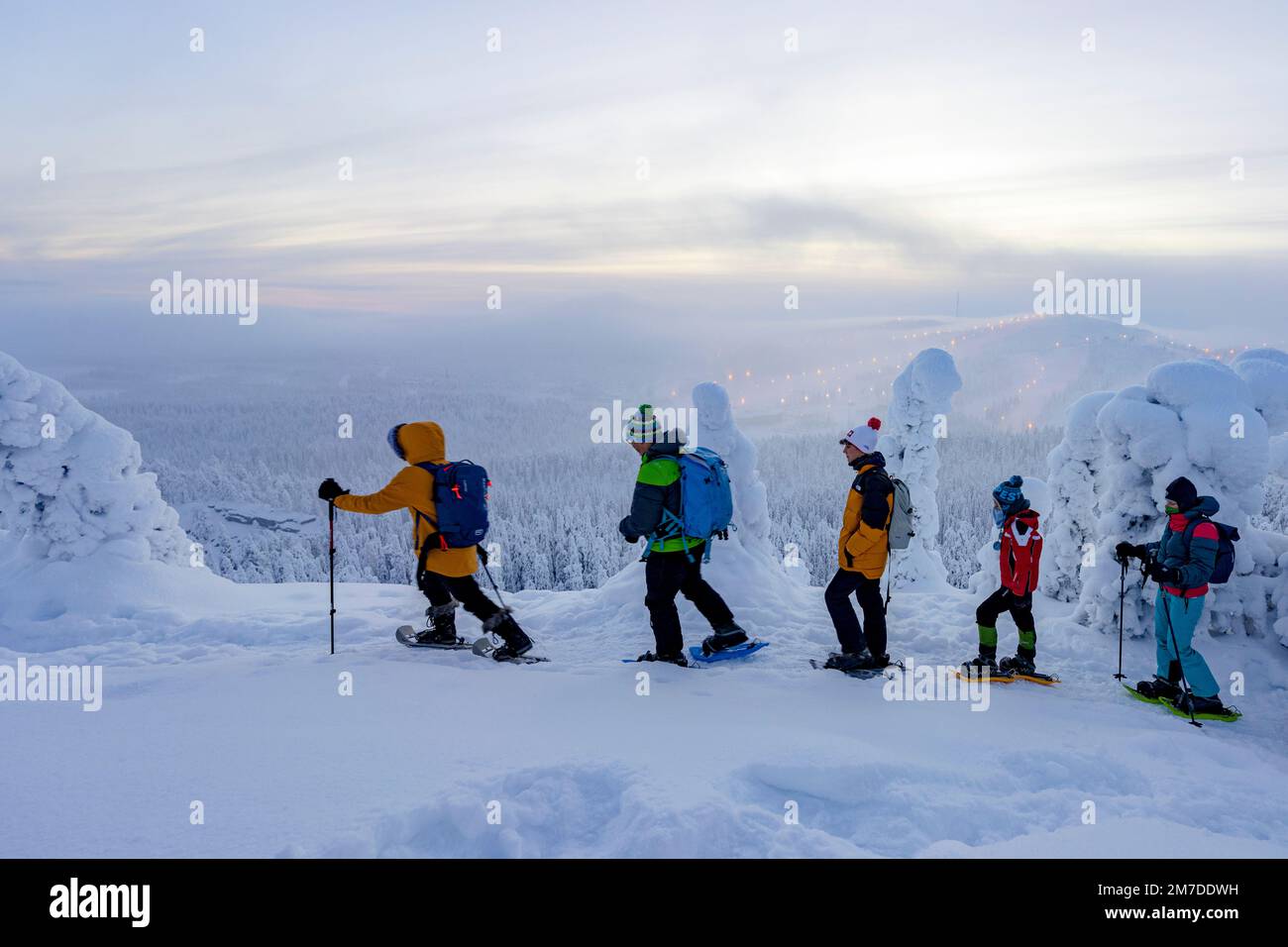 Eine Familie mit drei Kindern, die die Aussicht auf Schneeschuhwanderungen im gefrorenen Wald, Oulanka-Nationalpark, Ruka Kuusamo, Lappland, Finnland, genießen Stockfoto
