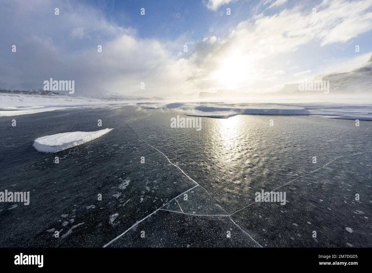 Die Sonne reflektiert auf dem Eis eines gefrorenen Sees im Winter, Stora Sjofallet, Norrbotten County, Lappland, Schweden Stockfoto