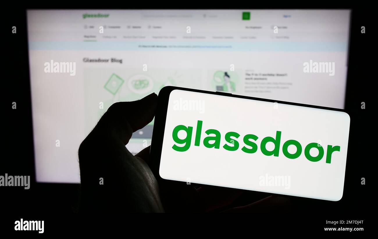 Person, die ein Mobiltelefon mit dem Logo des US-amerikanischen Unternehmens Glassdoor Inc. Auf dem Bildschirm vor der Unternehmenswebseite hält. Konzentrieren Sie sich auf das Display des Telefons. Stockfoto