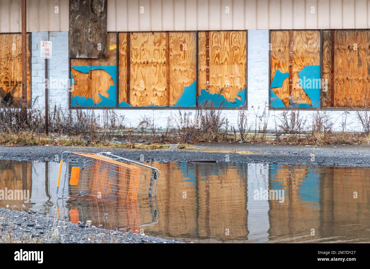 Ein Einkaufswagen in einem Wasserpool vor einem verlassenen Einkaufszentrum Stockfoto