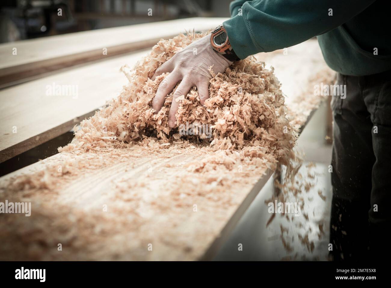 Möbelhersteller und Schreiner in seiner Werkstatt mit Holzbohlen und Holzspäne. Stockfoto