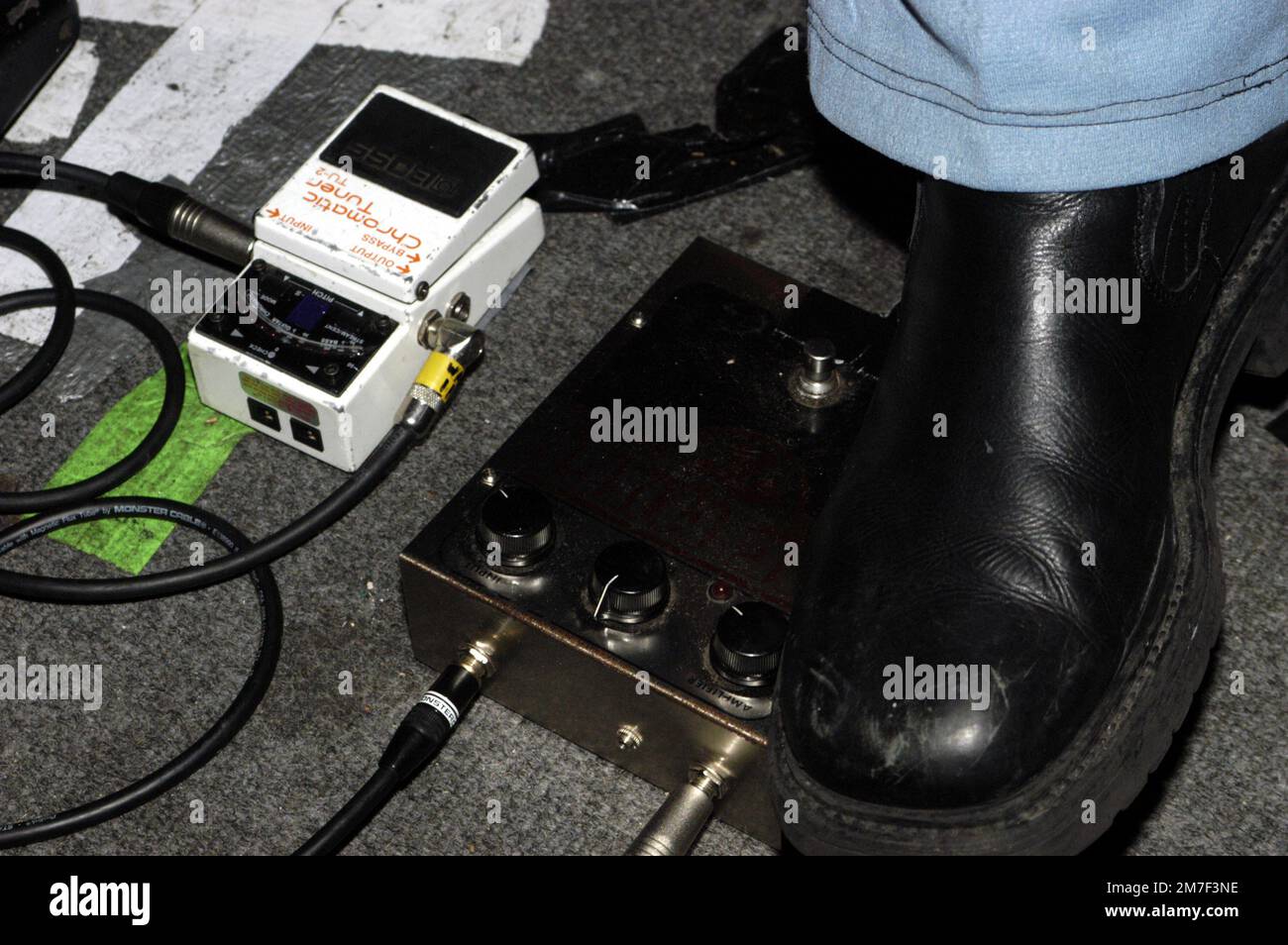 GITARRENPEDALE, CHROMATIC TUNER, ELECTRIC SIX, 2003: Die Gitarrenpedale und schwarzen Stiefel von Anthony Selph – alias Rock ‘n’ Roll Indian – Leadgitarrist von ELECTRIC SIX aus dem Jahr 1996-2003, der mit ihrem bahnbrechenden Hit „Danger! High Voltage' im Barfly in Cardiff am 2. Februar 2003. Foto: Rob Watkins. INFO: Electric Six, eine amerikanische Rockband, wurde Anfang der 2000er Jahre für ihre energiegeladenen Auftritte und eingängigen Songs wie „Danger! High Voltage“ und „Gay Bar“ vermischen Rock-, Disco- und Punkeinflüsse. Stockfoto
