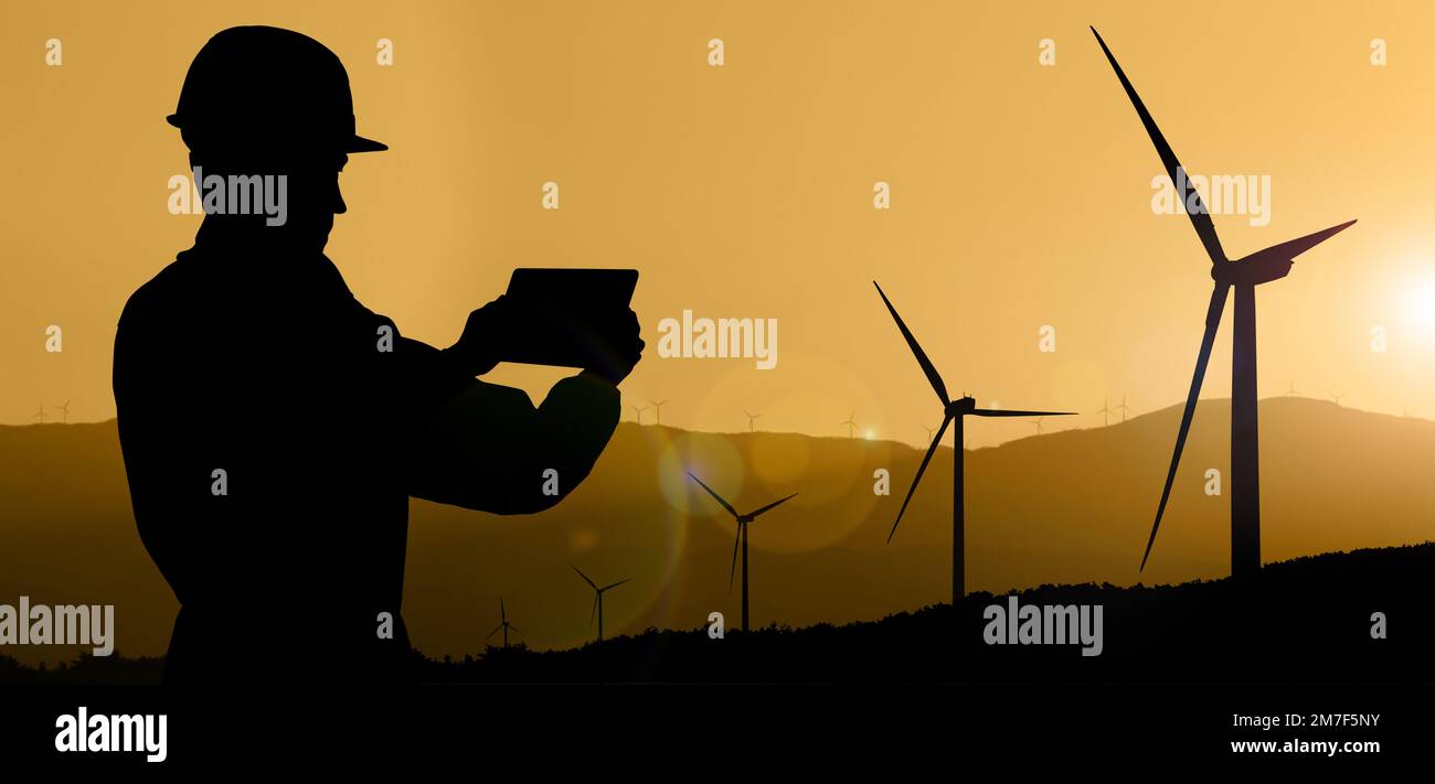 Silhouette eines Ingenieurs mit Tablet-Computer und Windturbinen bei Sonnenuntergang Stockfoto