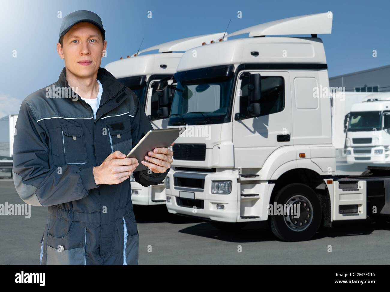 Manager mit einem digitalen Tablet neben Trucks. Flottenmanagement Stockfoto