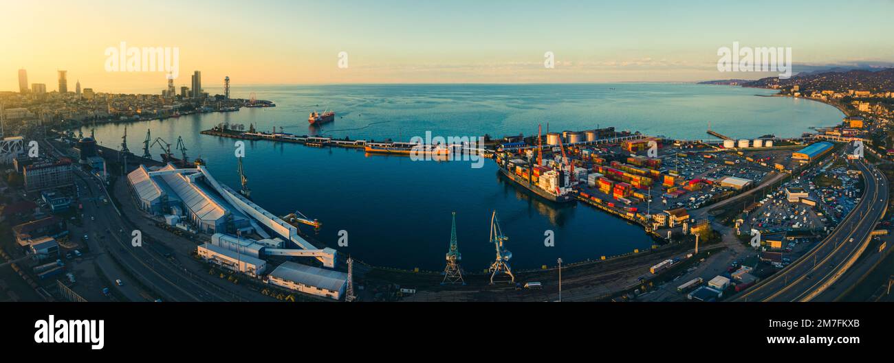Luftfrachtverkehr in Batumi mit Eisenbahn und Autobahn mit Autos; Hafenpanorama und Uferpromenade mit Sonnenuntergang über dem Horizont Skysc Stockfoto