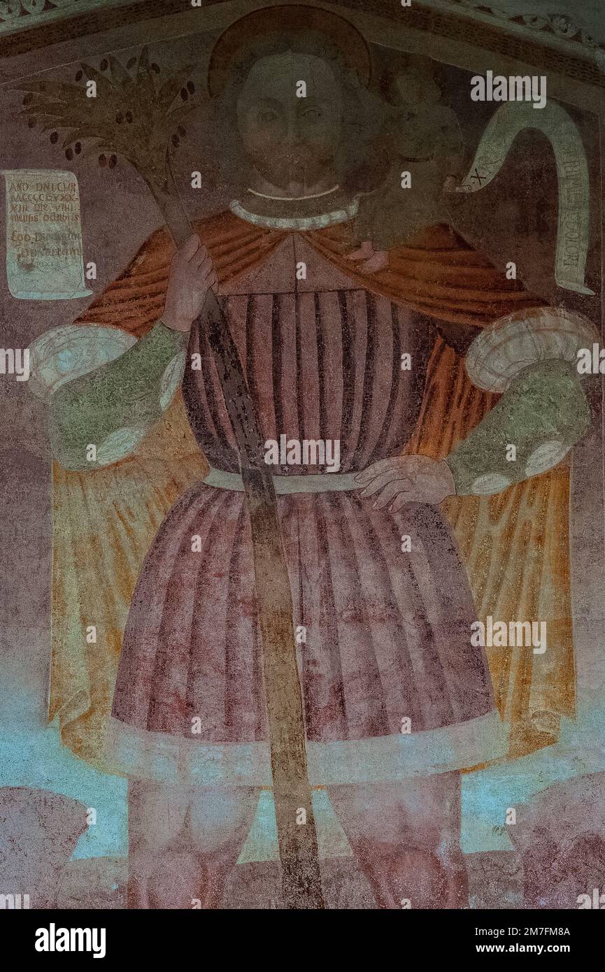 Eine Riesenfigur des hl. Christophorus, der das Christkind auf der Schulter trägt. Detail des Freskos aus der Vorrenaissance aus dem späten 15. Jahrhundert von Dionisio de Avevaria, Mitglied der Familie der Lombardischen Baschenis, an der Westfront der Chiesa di Sant’Antonio Abate (Kirche des Heiligen Antonius des Abtes) in Pelugo, Trentino-Südtirol, Italien. Stockfoto