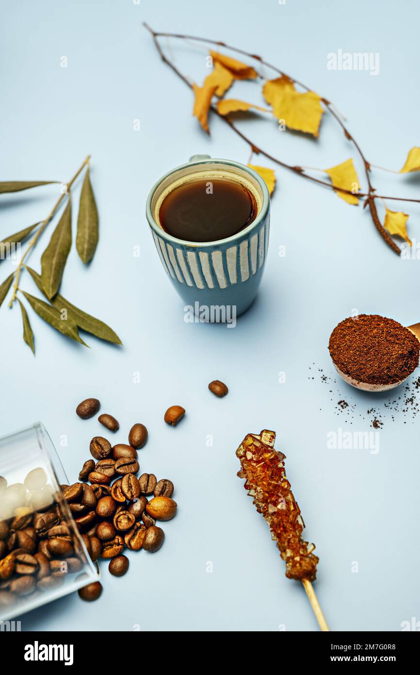 Eine kleine Espresso-Tasse aus blauem Porzellan auf einem einfachen blauen Metalltisch mit Kaffeebohnen und anderen Artikeln Stockfoto