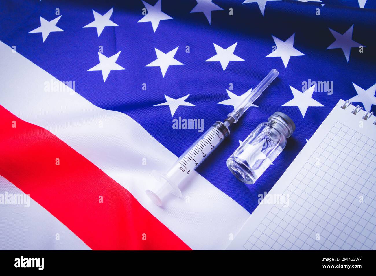 Spritze und Impfstoff auf dem Hintergrund der amerikanischen Flagge. Impfungen in sasha. Leeres Notizbuch für Impfprotokolle. Stockfoto