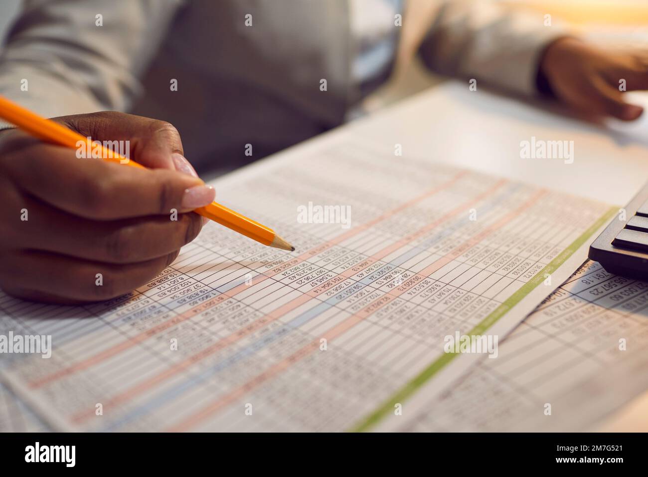 Finanzbuchhalter, der im Büro sitzt, Papierkram erledigt und mit Tabellenkalkulationen arbeitet Stockfoto