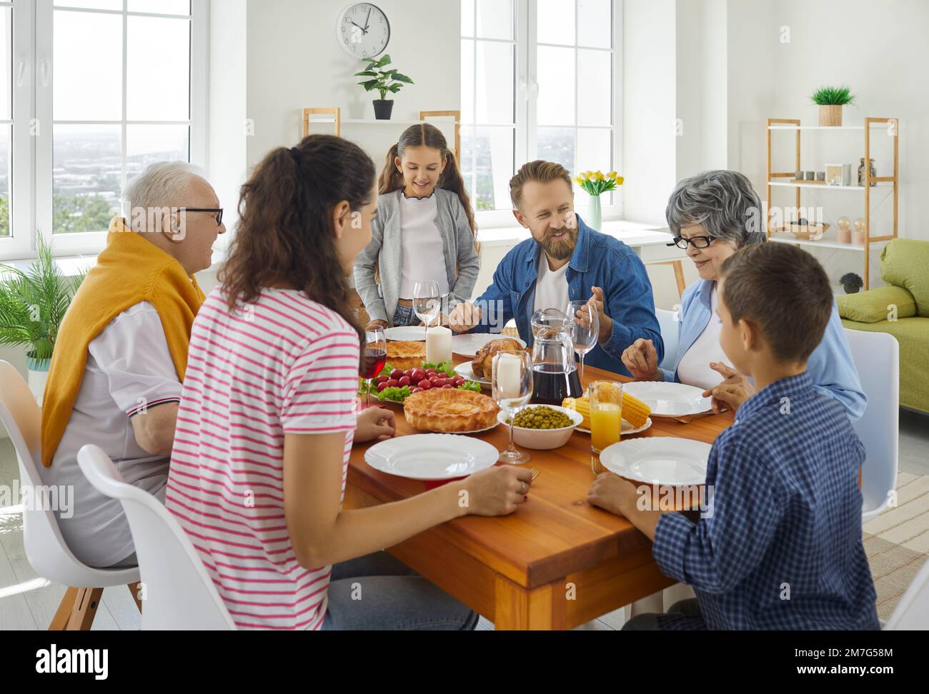 Familieneltern, Großeltern und Kinder, die zu Mittag essen und sich am Tisch unterhalten. Stockfoto