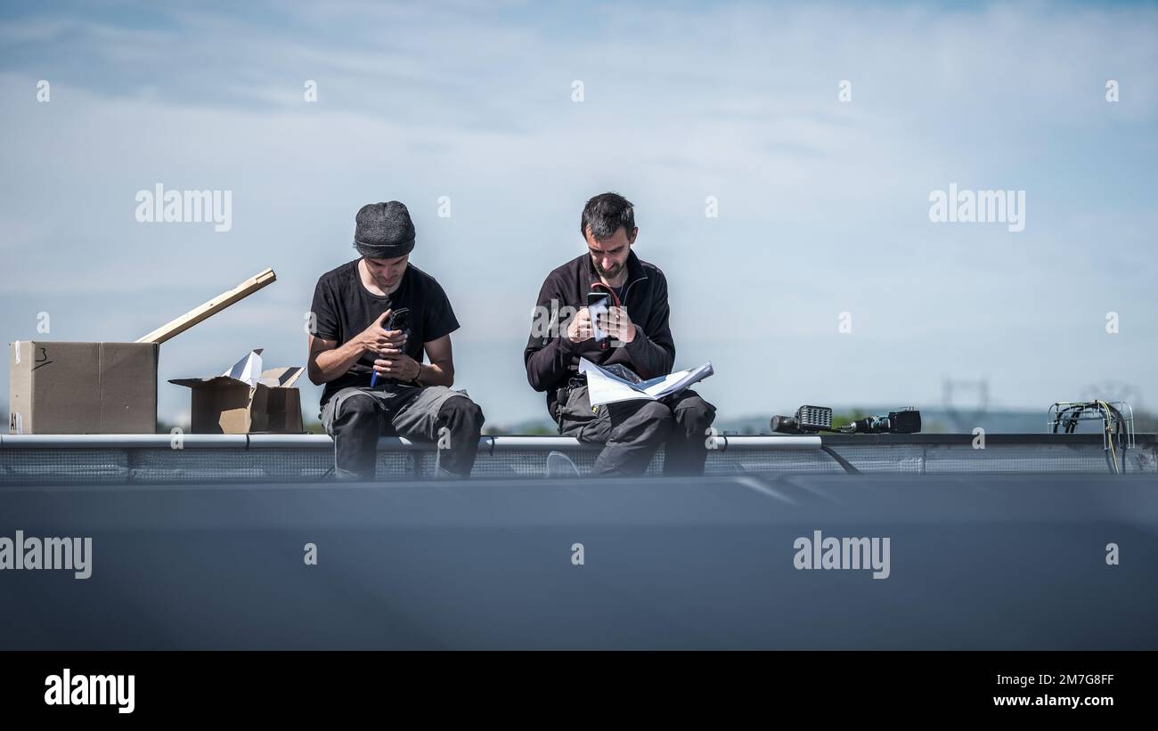 Arbeiterteam, das elektrische Anschlusskabel für Solarpaneele vorbereitet Stockfoto