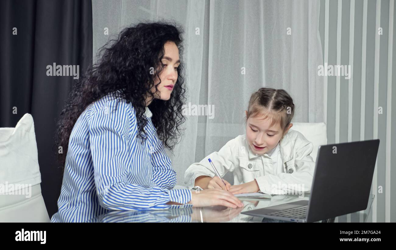 Mutter hilft der Tochter, Material des Online-Unterrichts zu verstehen Stockfoto
