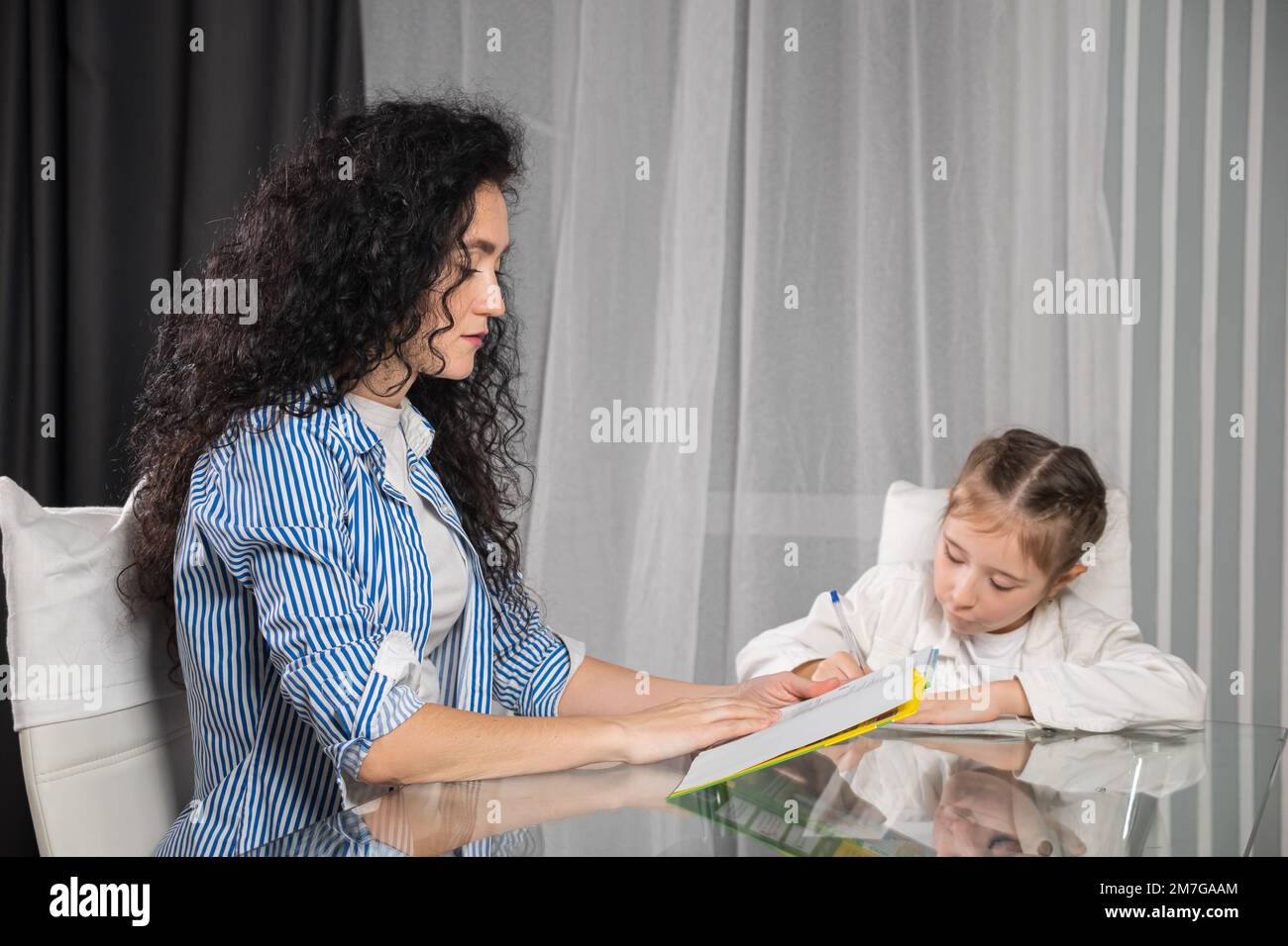 Nervöse Mutter hilft der Tochter bei Hausaufgaben zu Hause Stockfoto