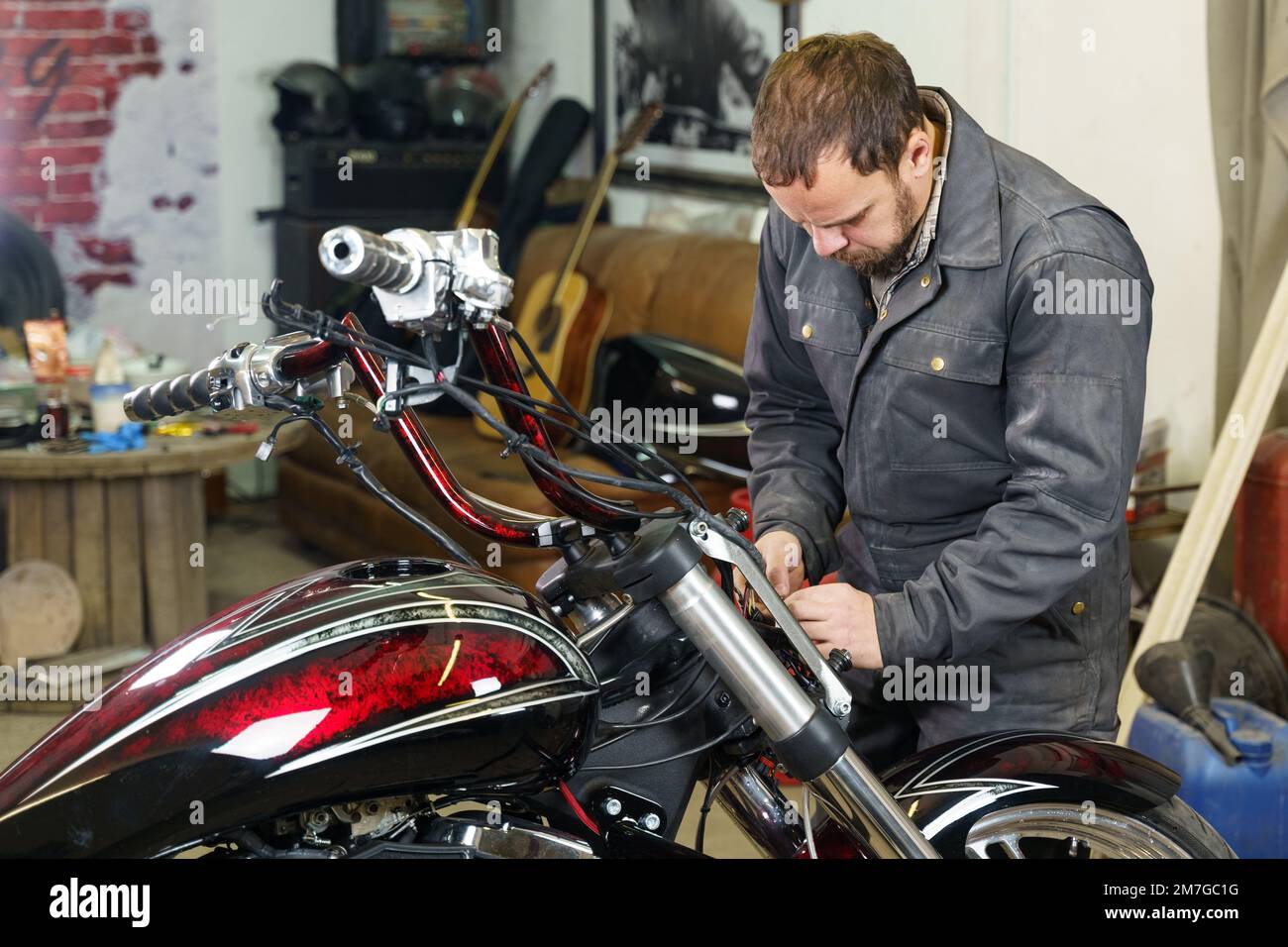 Der Mechaniker schließt die elektrischen Kabel des Motorrads an. Transportkonzept. Stockfoto