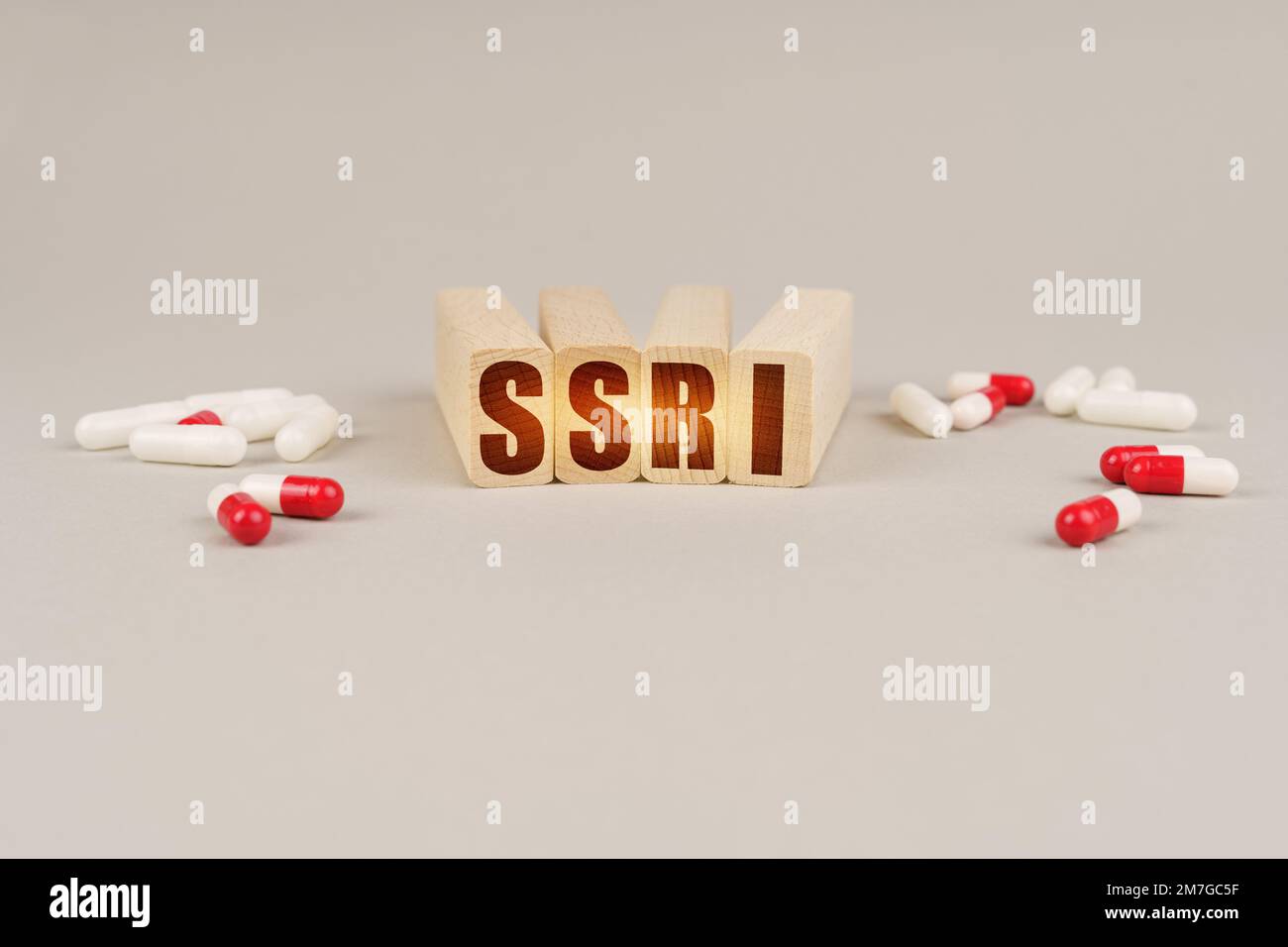Medizinisches Konzept. Auf einer grauen Oberfläche sind Pillen und ein roter Holzblock mit der Aufschrift - SSRI Stockfoto