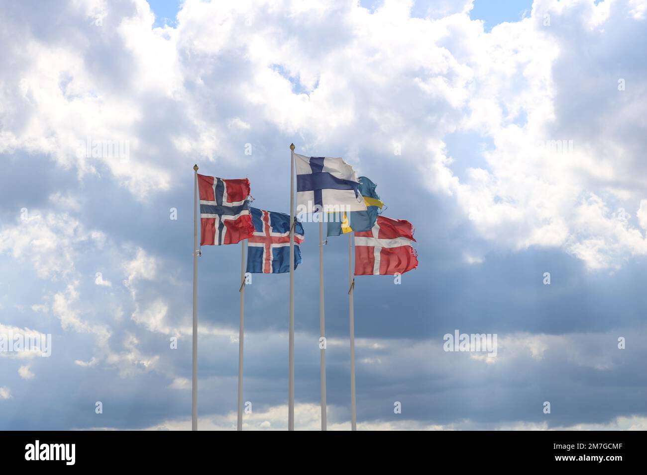 Eine Nahaufnahme der Flaggen Norwegens, Islands, Finnlands, Dänemarks und Schwedens, die in der Luft vor einem blauen Himmel winken Stockfoto