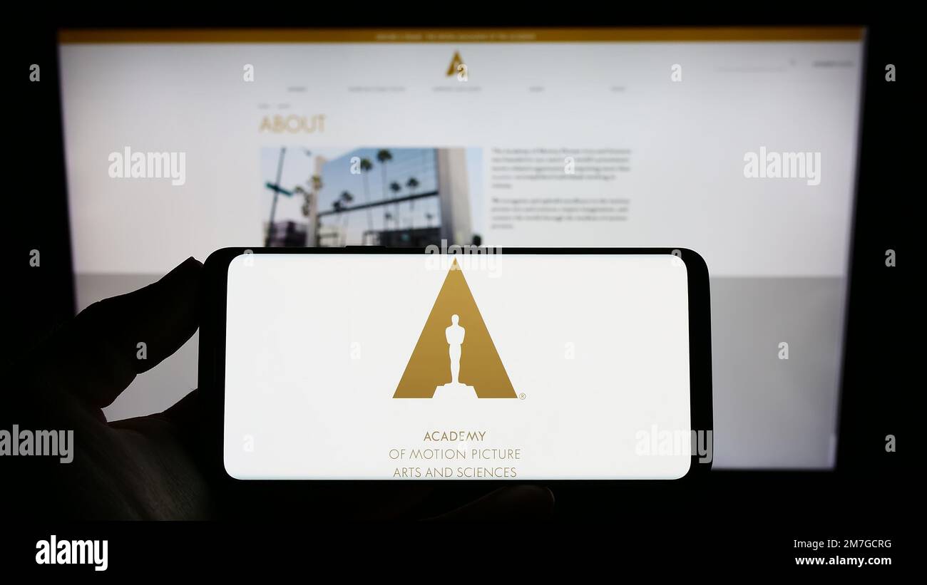 Person, die ein Mobiltelefon mit dem Logo der Academy of Motion Picture Arts and Sciences (AMPAS) auf dem Bildschirm vor der Webseite hält. Konzentrieren Sie sich auf das Display des Telefons. Stockfoto