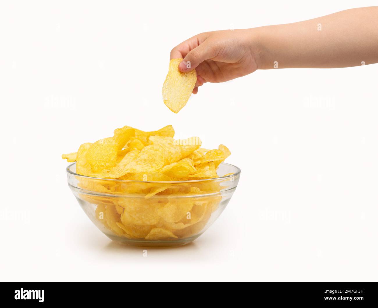 Nahaufnahme der Hand eines Kindes, die einen Kartoffelchip fängt oder mit weißem Hintergrund gebraten wird Stockfoto