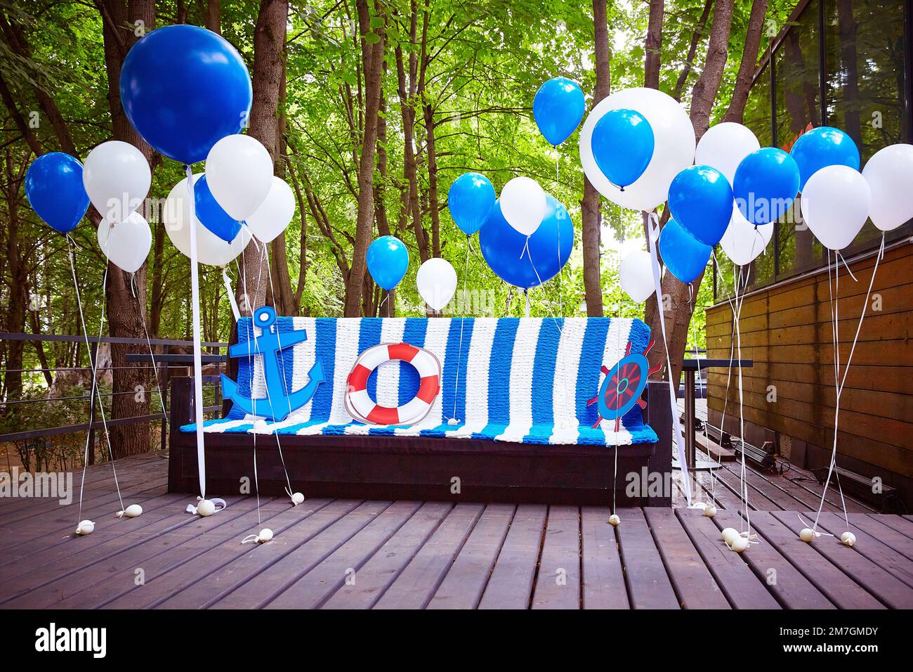 Fotozone im Marinestil in Blau und Weiß. Ballons und ein Sofa mit Karomuster sind für ein Geburtstagsfoto dekoriert. Stockfoto