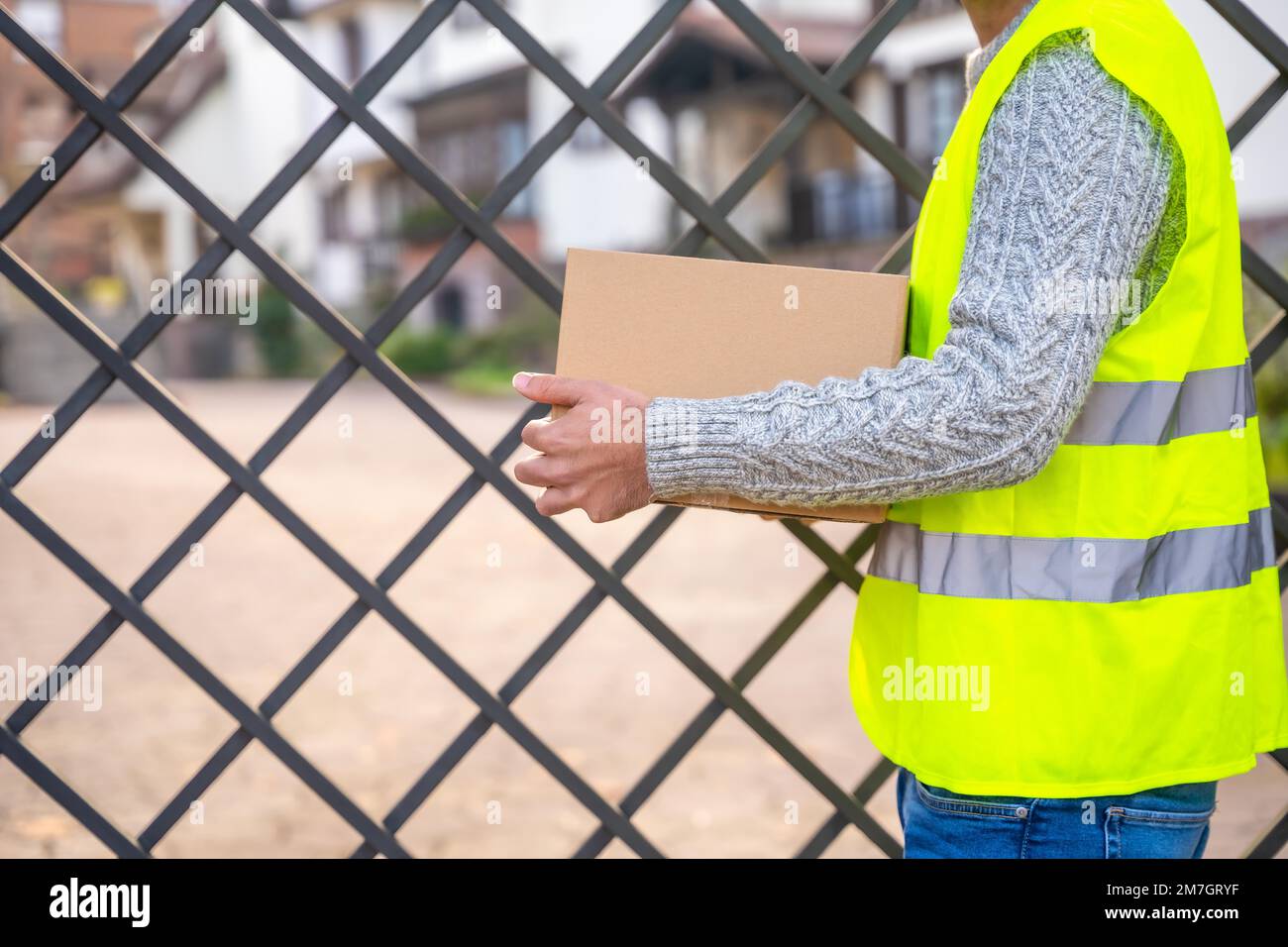Paketzustellarbeiter eines Online-Shops, der außerhalb des Hauses auf den Kunden wartet Stockfoto