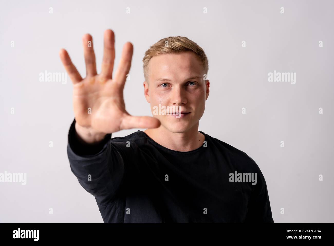 Attraktives blondes deutsches Model in einem schwarzen Trikot auf weißem Hintergrund, stoppt Rassismus, stoppt Homophobie Stockfoto
