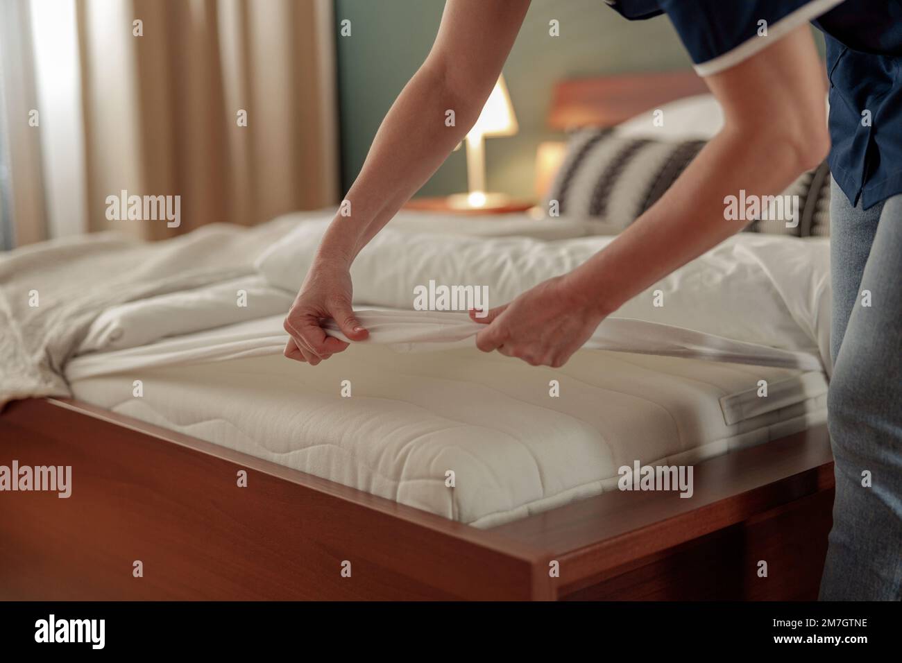 Nahaufnahme der Putzfrau, die im Hotelzimmer das Housekeeping und das Bettenmachen macht Stockfoto