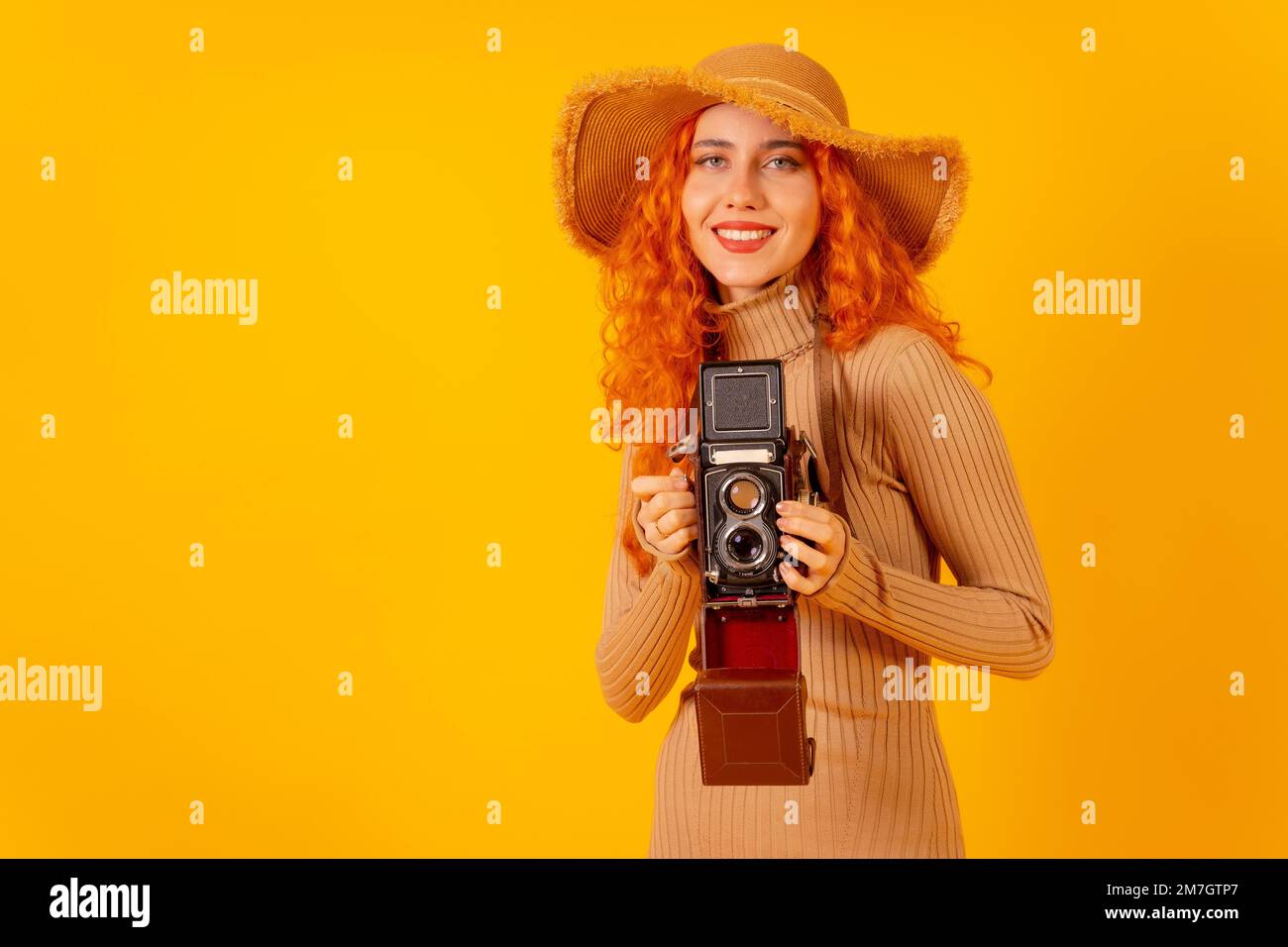Rothaarige Touristin auf gelbem Hintergrund, Studioaufnahme, mit einer Oldtimer-Kamera Stockfoto Rothaarige Touristin auf gelbem Hintergrund, Studioaufnahme, mit einer Oldtimer-Kamera Stockfoto