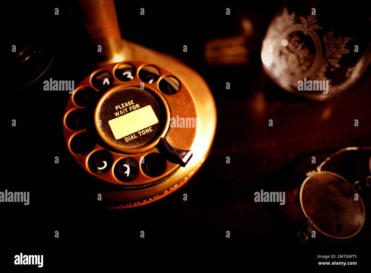 Basis eines frühen 1900er Jahre alten Western Electric Brass Bullnose Candlestick Drehwahltelefons mit Bitte warten Sie auf das Wählton-Skript auf der Nummer wählen. Stockfoto