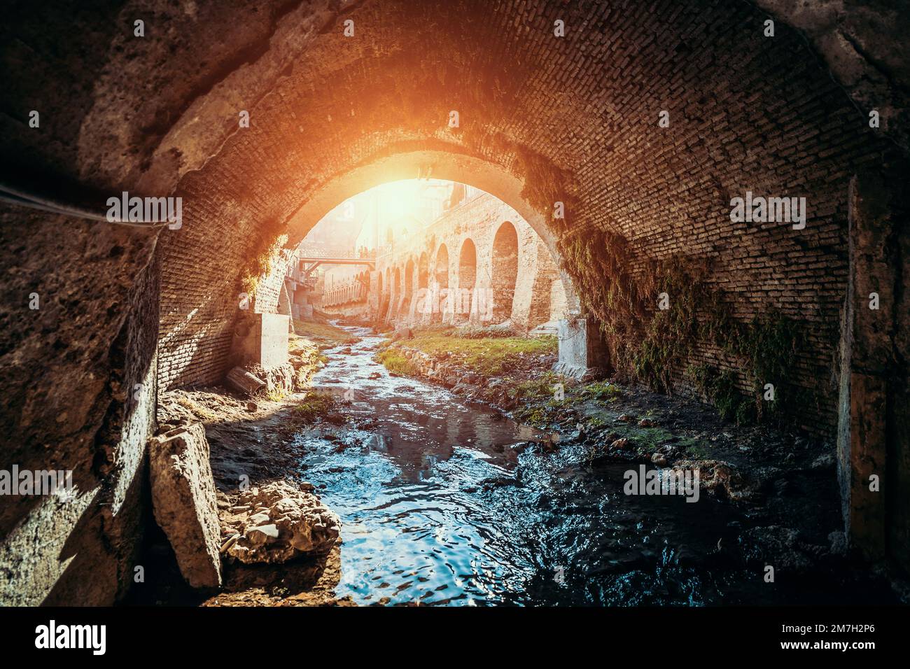 Blick vom Inneren des Kanalisationstunnels, des alten Tunnels für den Fluss oder des Abwassers mit Sonnenlicht. Stockfoto