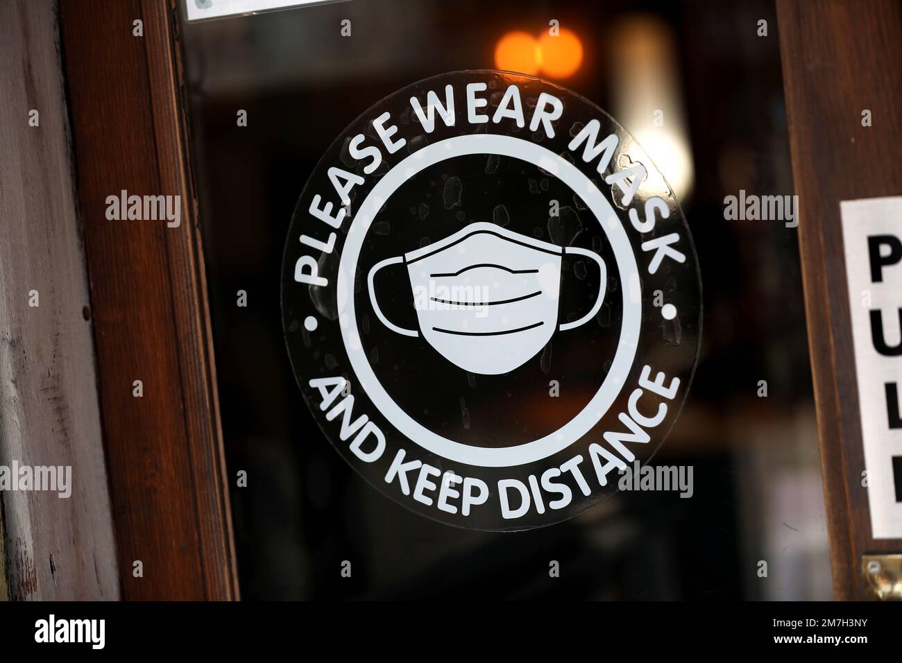 Bitte tragen Sie eine Maske und halten Sie das Distanzschild in Sussex, Großbritannien. Stockfoto