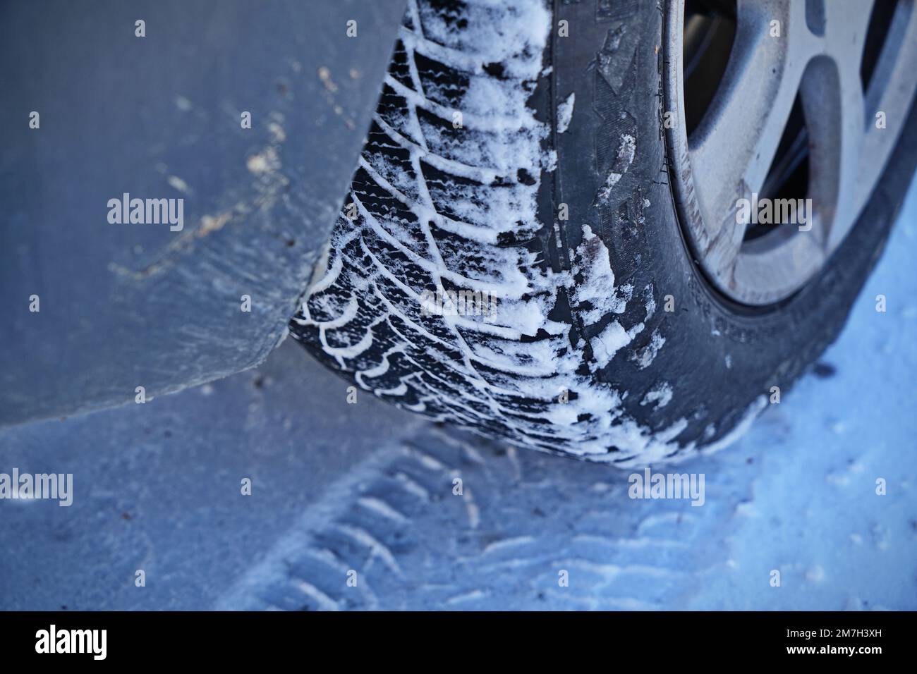 Auto mit Winterreifen auf Schneestraße fahren Stockfoto