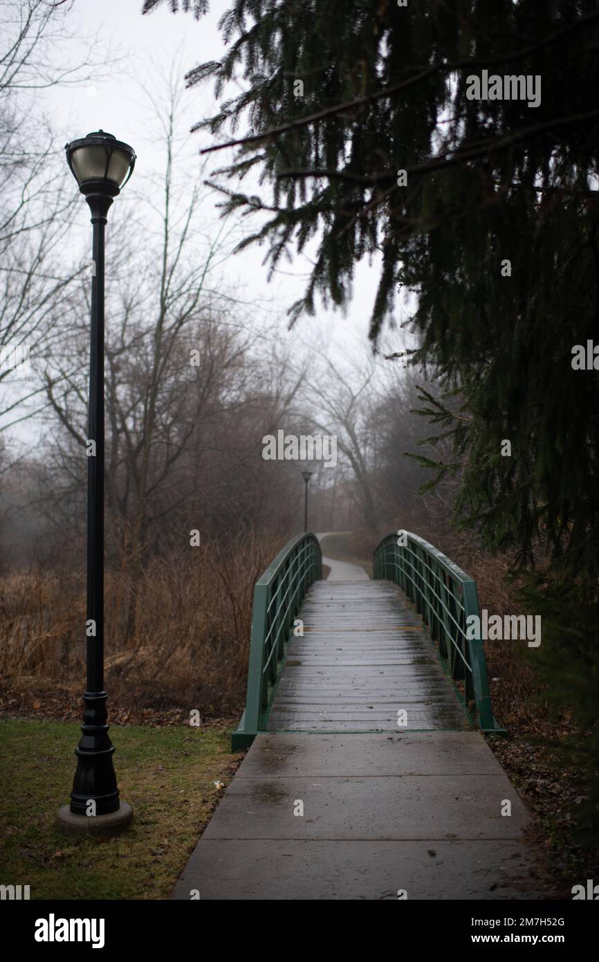 Rainy Bridge Path mit Straßenlaternen an einem nebligen Wintertag Stockfoto