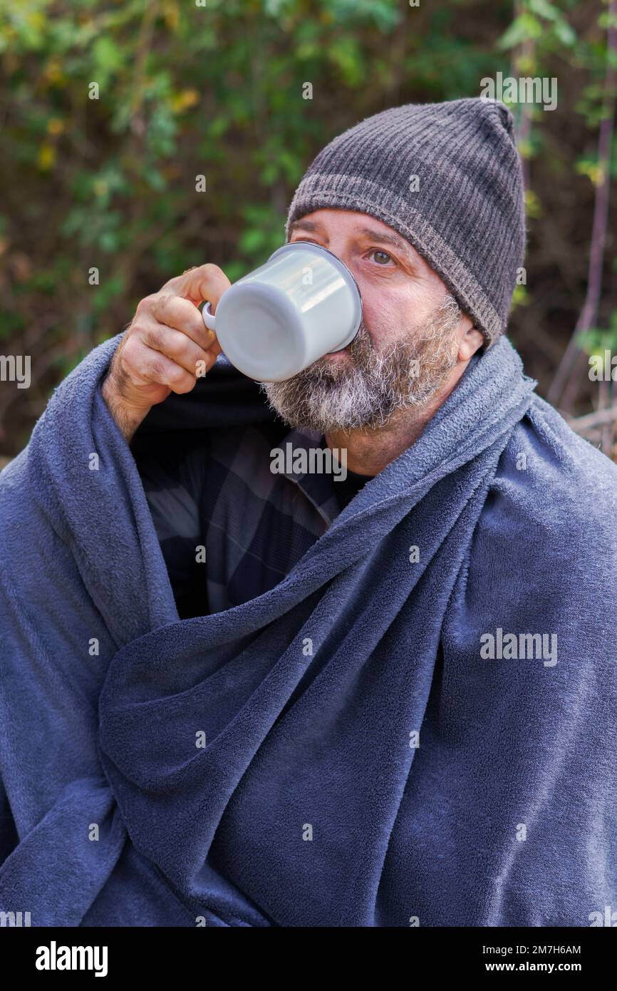 Ein Mann auf einem Campingausflug, der eine Tasse Kaffee trinkt Stockfoto