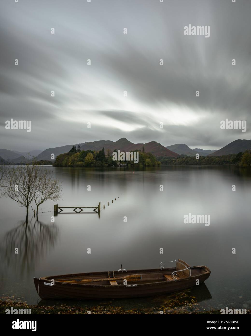 Langzeitaufnahme eines Ruderboots auf Derwentwater, Keswick, mit Tor, Derwent Isle und Cat Bells im Hintergrund und im See reflektiert Stockfoto