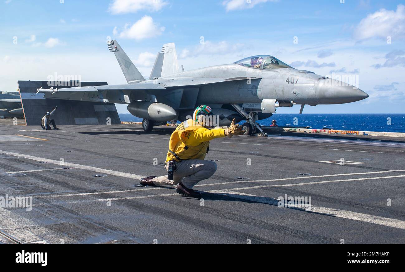 Philippinen-Meer, Internationale Gewässer. 27. Dezember 2022. Ein Navy Yellow Vest Aircraft Shooter der USA leitet ein F/A-18E Super Hornet-Kampfflugzeug, mit dem Blue Diamonds of Strike Fighter Squadron 146, das vom Flugdeck des Flugzeugträgers der Nimitz-Klasse USS Nimitz während des Routineeinsatzes am 27. Dezember 2022 in der Philippinen See gestartet werden soll. Kredit: MC2 Justin McTaggart/USA Navy/Alamy Live News Stockfoto