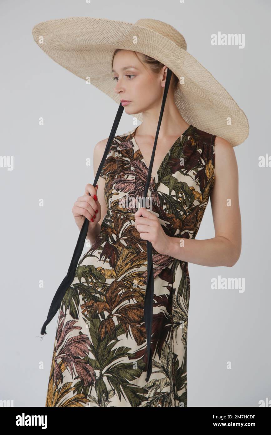 Eine Reihe von Studiofotos eines jungen weiblichen Models in einem ärmellosen Wickelkleid mit farbenfrohem tropischem Muster Stockfoto