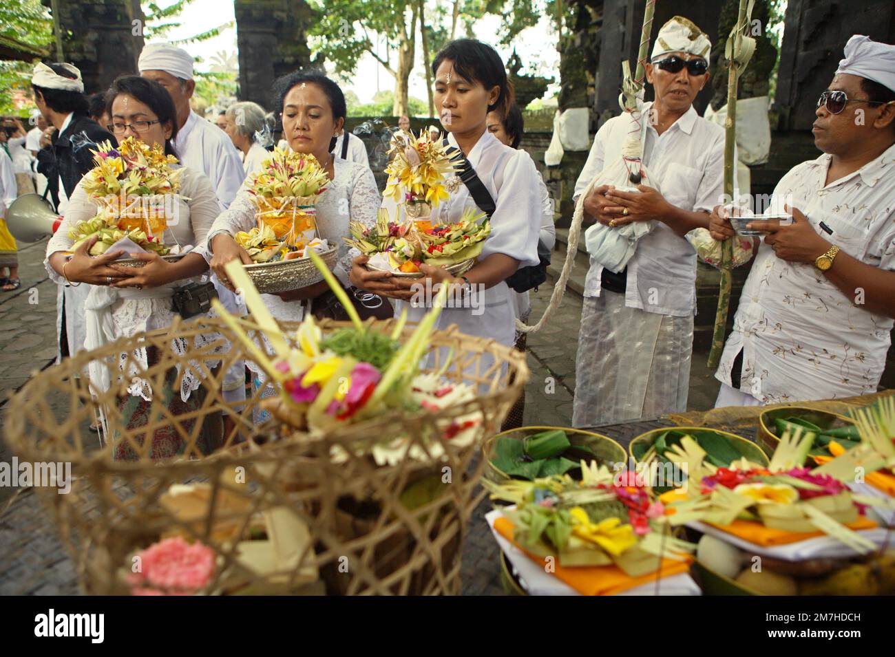 Frauen eines balinesischen Clans bringen spirituelle Opfer während einer Prozession mit, um die Geister ihrer verstorbenen Familienmitglieder zu ehren und zu reinigen, in einem Tempel in der Besakih-Tempelanlage, am Hang des Agung in Karangasem, Bali, Indonesien. Stockfoto